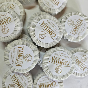Multiple round soap bars with 'Camellia Residences' branding on a light background